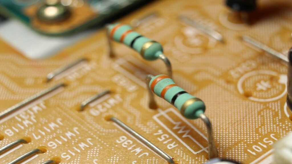 Bright blue resistors with red and gold stripes on a yellow circuit board
