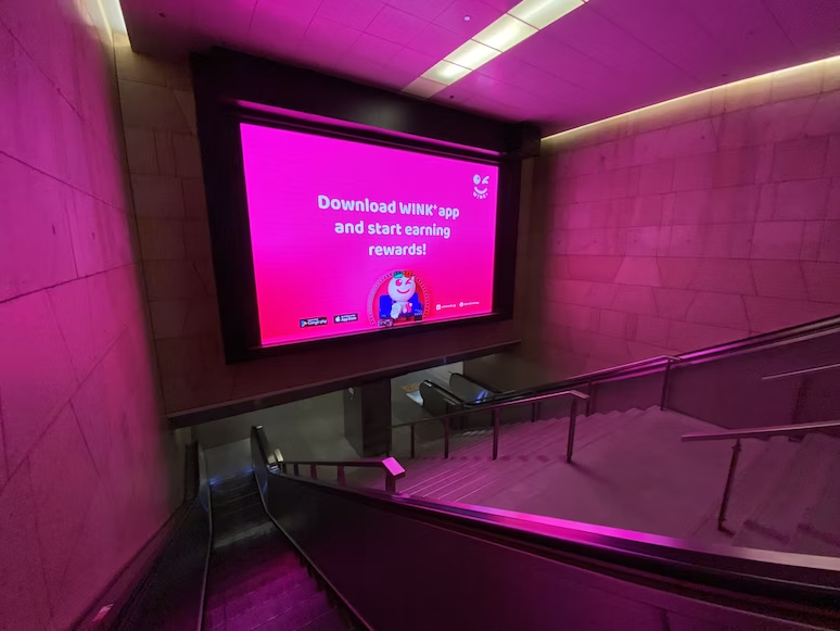 Large advertising screen at the bottom of a set of stairs