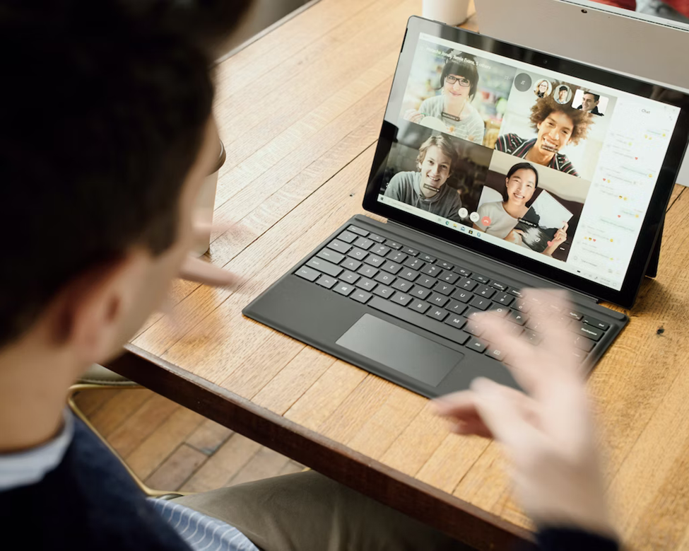 An individual takes a video call with four other people on the screen